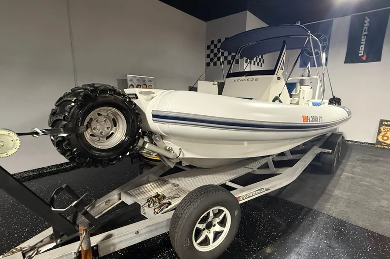 Slide: The Image of 2021 Sealegs 7.5M RIB on trailer, featuring amphibious wheels, in showroom setting. - 1