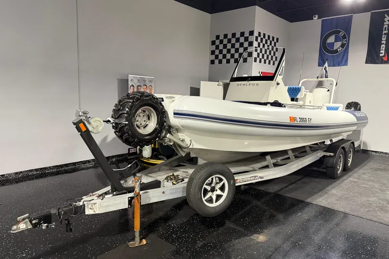 Slide: The Image of 2021 Sealegs 7.5M RIB on trailer in showroom with checkered flag decor. - 44