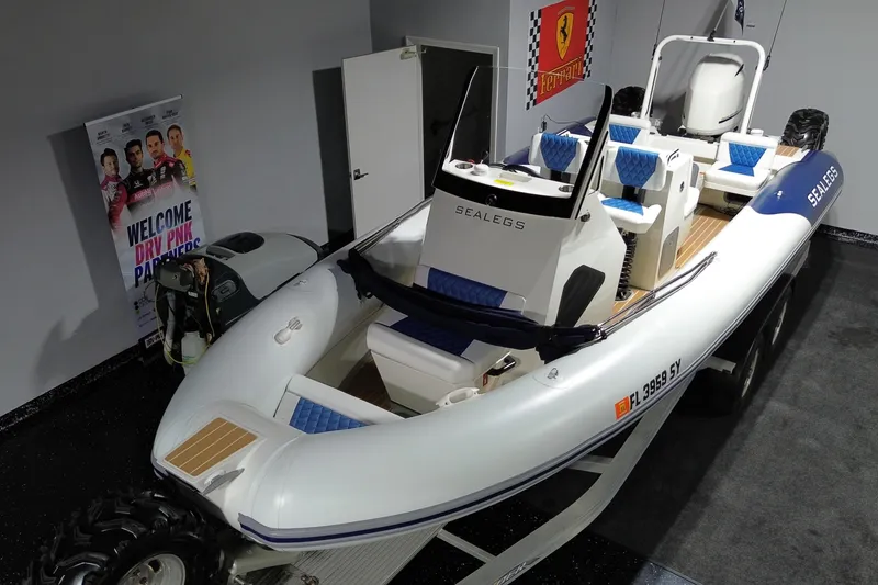 Slide: The Image of 2021 Sealegs 7.5M RIB boat in showroom with blue seating and Ferrari poster. - 5