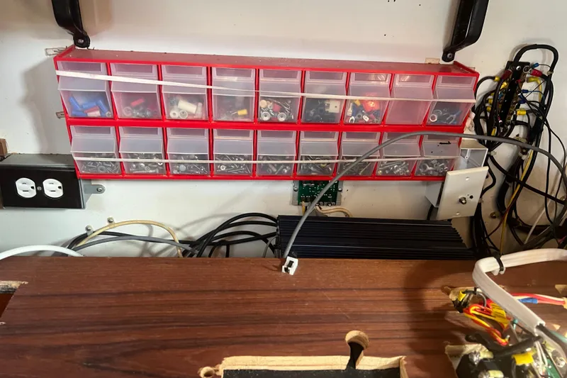 Slide: The Image of Workshop storage with organized hardware, electrical components, and wiring on a 1993 Compac Sloop. - 12