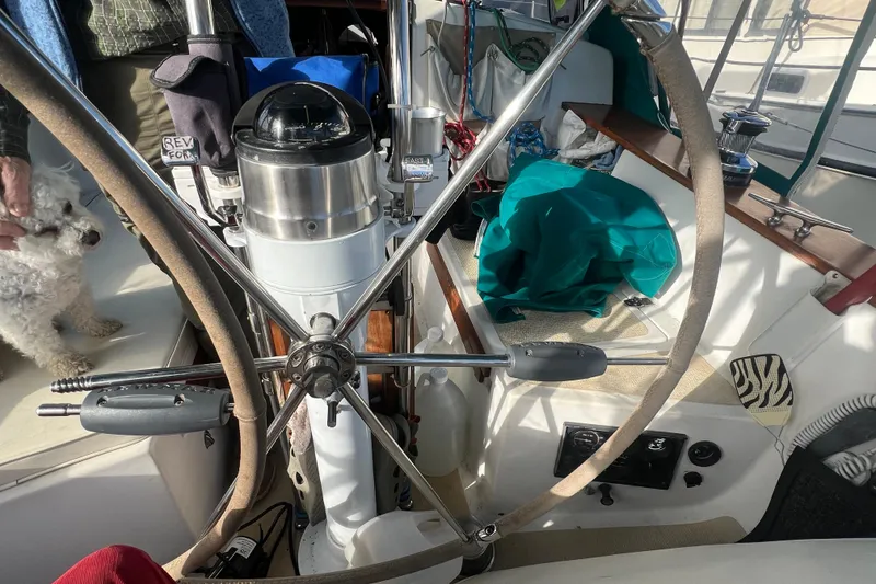 Slide: The Image of 1993 Compac Sloop cockpit with steering wheel, navigation equipment, and a small dog. - 18