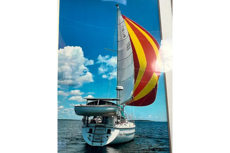 Slide: The Image of 1993 Compac Sloop sailing with colorful spinnaker under clear blue sky. - 21