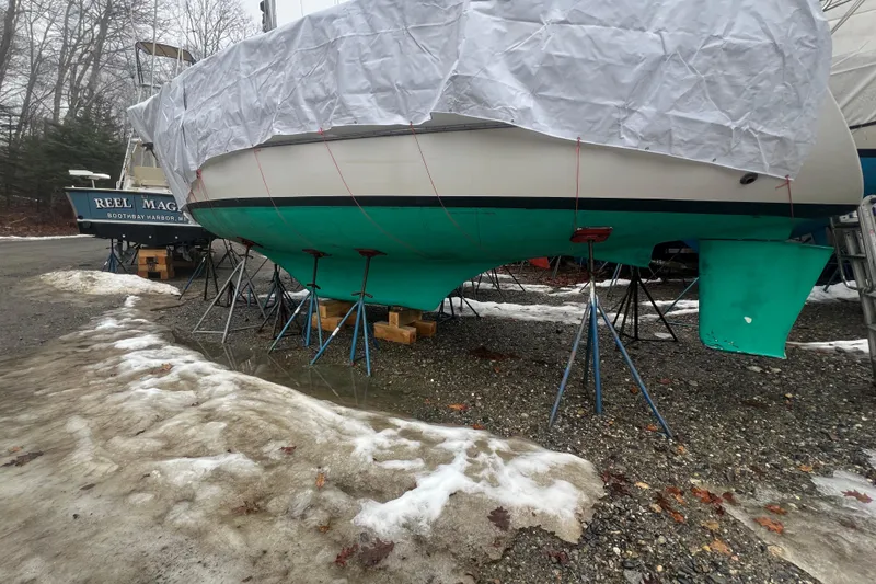 Slide: The Image of 1993 Com-Pac Sloop sailboat on stands, covered, with snow and trees in the background. - 23