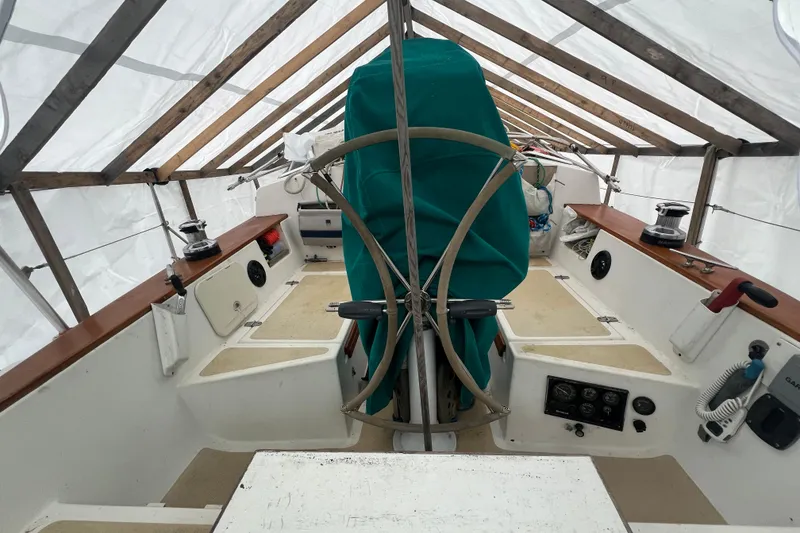 Slide: The Image of 1993 Com-Pac Sloop sailboat cockpit under protective cover, featuring steering wheel and equipment. - 24