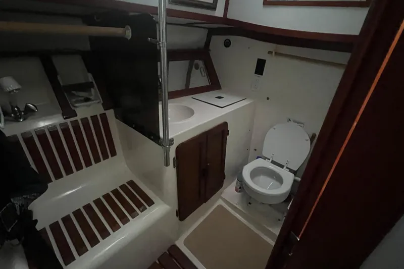 Slide: The Image of 1993 Com-Pac Sloop interior bathroom with toilet, sink, and wooden accents. - 31