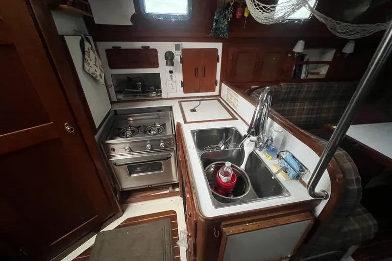 Slide: The Image of Compact kitchen area in a 1993 Com-Pac Sloop sailboat, featuring stove and sink. - 33