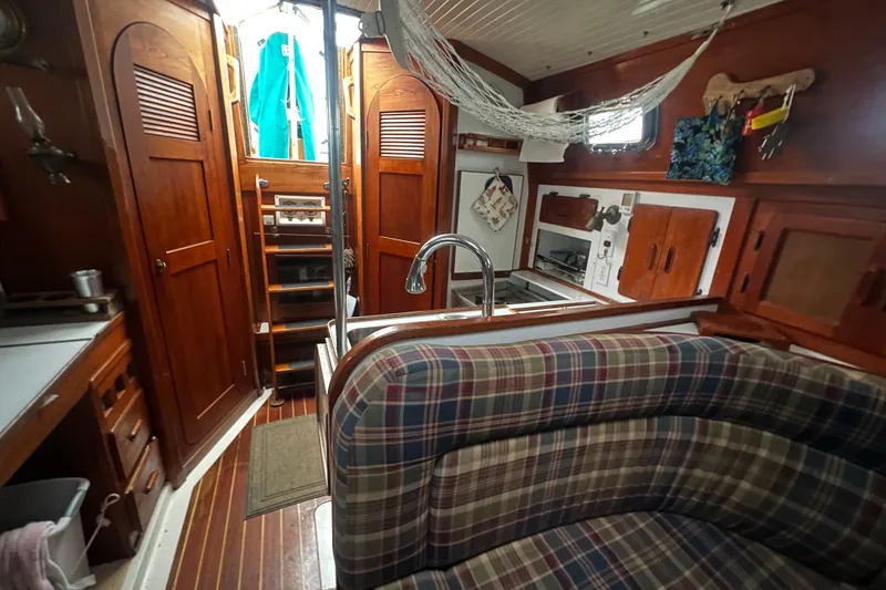 Slide: The Image of Cozy 1993 Com-Pac Sloop interior with plaid seating, wooden cabinetry, and compact kitchen area. - 35