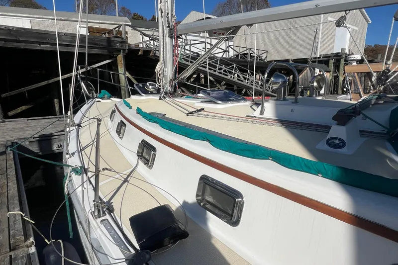 Slide: The Image of 1993 Compac Sloop sailboat docked, featuring a clean deck and vibrant green trim. - 7