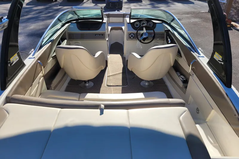Slide: The Image of 2013 Sea Ray 210 SLX boat interior with beige seating and modern dashboard. - 8