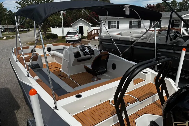 Slide: The Image of 2026 Starcraft SVX 211 OB boat with canopy, modern interior, and sleek design in a residential area. - 5