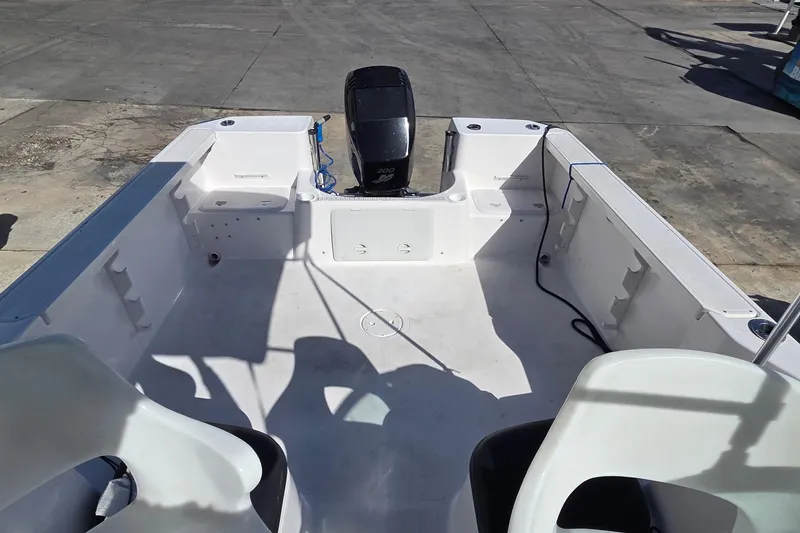 Slide: The Image of 2001 Pro-Line 22 Walk boat interior with seating and motor, docked on concrete. - 9