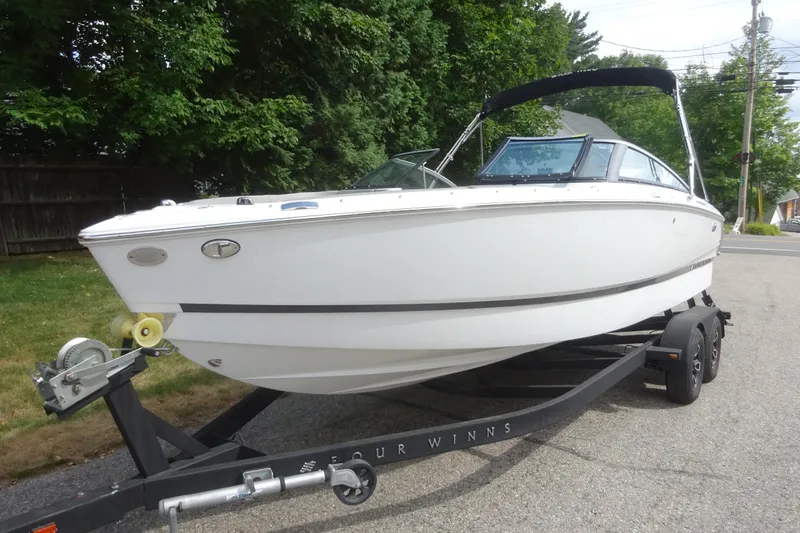 Slide: The Image of 2022 Four Winns H4 OB boat on trailer, parked outdoors near trees. - 5