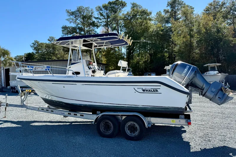 Slide: The Image of 2001 Boston Whaler 230 Outrage boat on trailer, parked outdoors. - 7