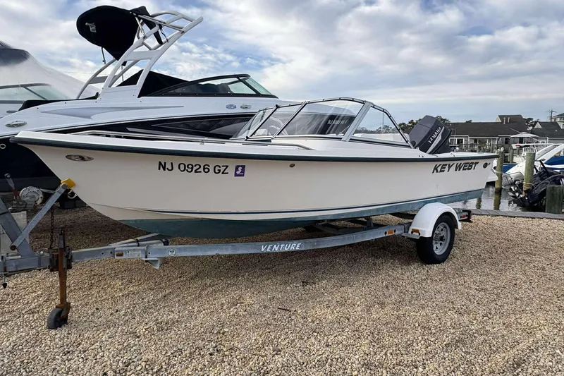 Slide: The Image of 2006 Key West 1720 Dual Console boat on trailer, parked on gravel near marina. - 3