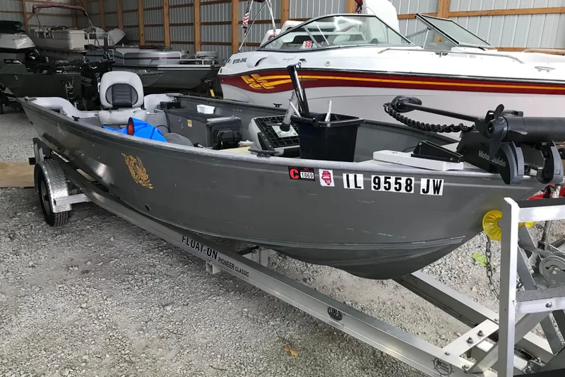 The Image of 2004 Crestliner Canadian 18 Tiller boat on trailer in storage facility. - 1