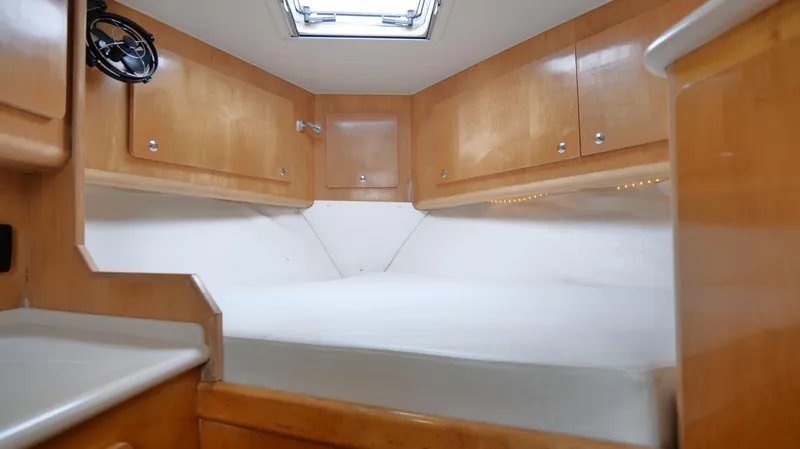 Slide: The Image of 2006 Out Island 38 Express cabin interior with wood cabinetry and white bedding. - 22