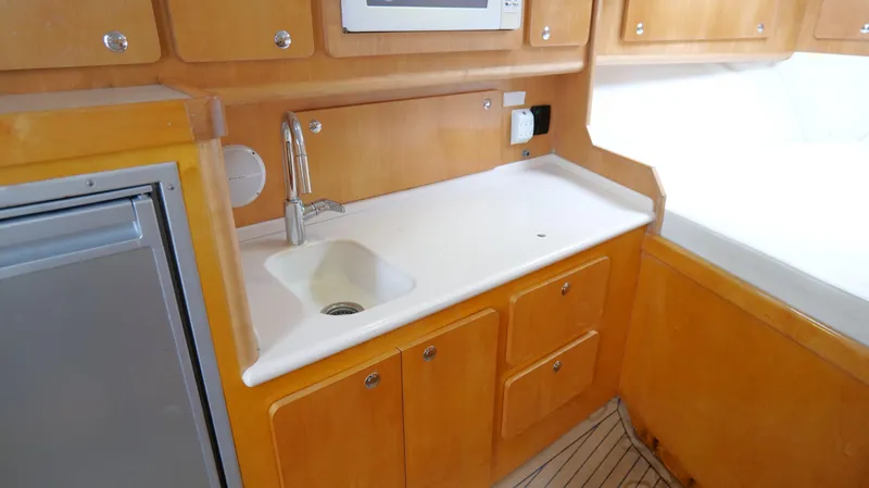 Slide: The Image of 2006 Out Island 38 Express yacht kitchen with wooden cabinets and compact sink. - 24