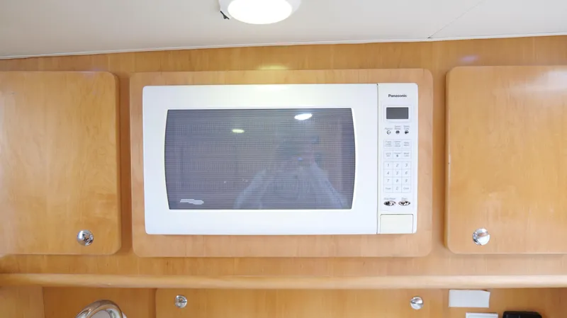 Slide: The Image of Microwave in 2006 Out Island 38 Express yacht kitchen, surrounded by wooden cabinets. - 25