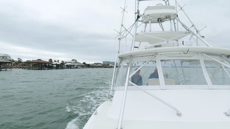 Slide: The Image of Out Island 38 Express 2006 cruising near coastal homes on a cloudy day. - 46