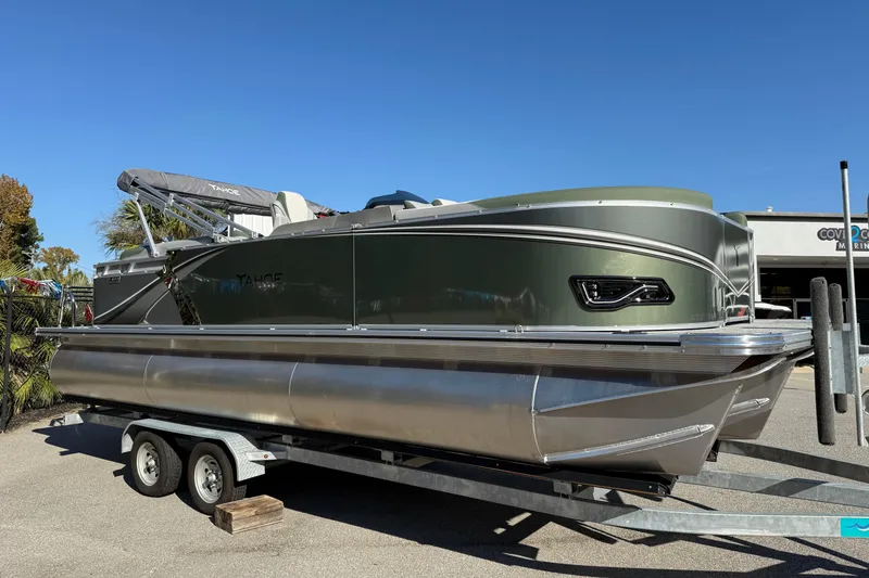 Slide: The Image of 2026 Tahoe Pontoon LTZ Quad Lounger on trailer, sleek design, green exterior. - 1