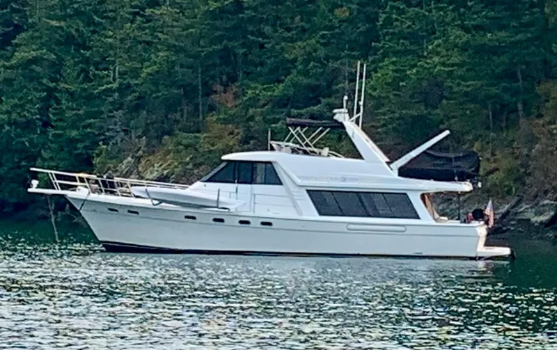 Slide: The Image of 1994 Bayliner 4788 Pilot House Motoryacht on tranquil water near forested shoreline. - 1