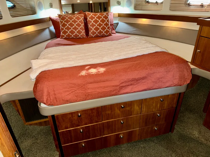 Slide: The Image of Cozy bedroom in 1994 Bayliner 4788 Pilot House Motoryacht with orange bedding and wood accents. - 13