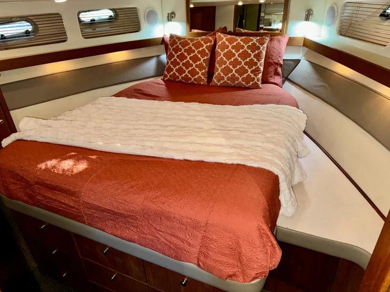 Slide: The Image of Cozy bedroom in 1994 Bayliner 4788 Pilot House Motoryacht with orange bedding and decorative pillows. - 16