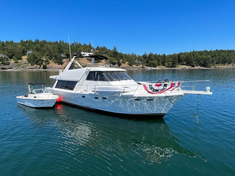 Slide: The Image of 1994 Bayliner 4788 Pilot House Motoryacht anchored in scenic waters with festive decor. - 2