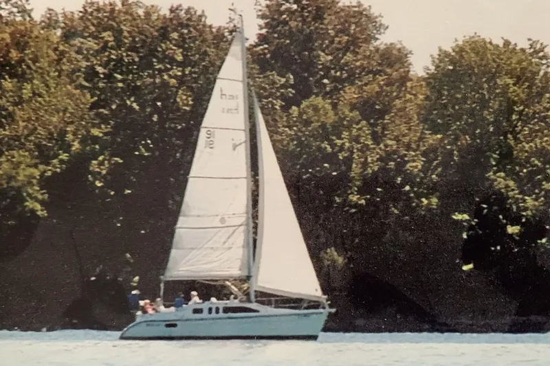 The Image of Sailboat Hunter 29.5 from 1994 sailing near a wooded shoreline. - 2