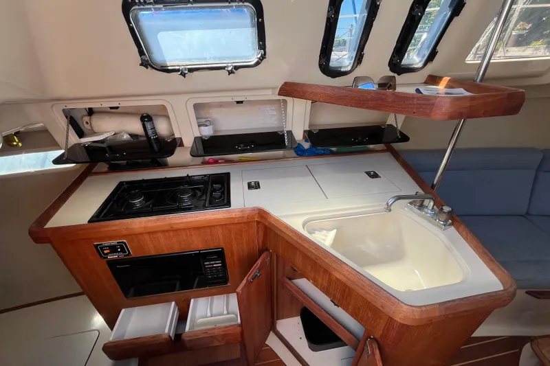 Slide: The Image of 1994 Hunter 29.5 sailboat interior kitchen with stove, sink, and storage compartments. - 30