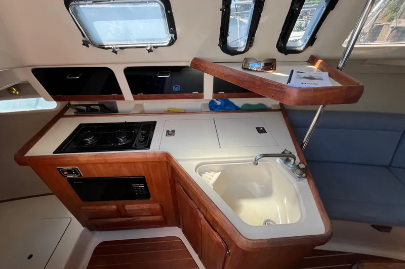 Slide: The Image of 1994 Hunter 29.5 yacht interior with kitchen, stove, sink, and seating area. - 31