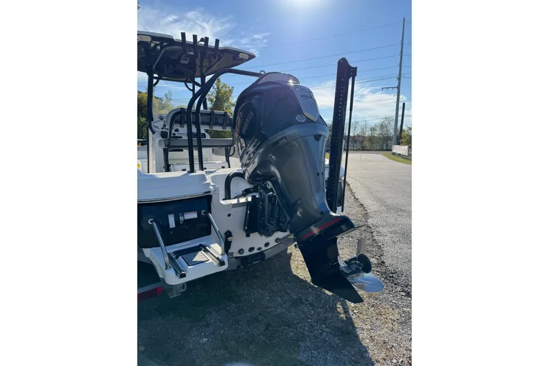 Slide: The Image of 2024 NauticStar 231 Hybrid boat with powerful outboard motor, parked on a sunny day. - 2