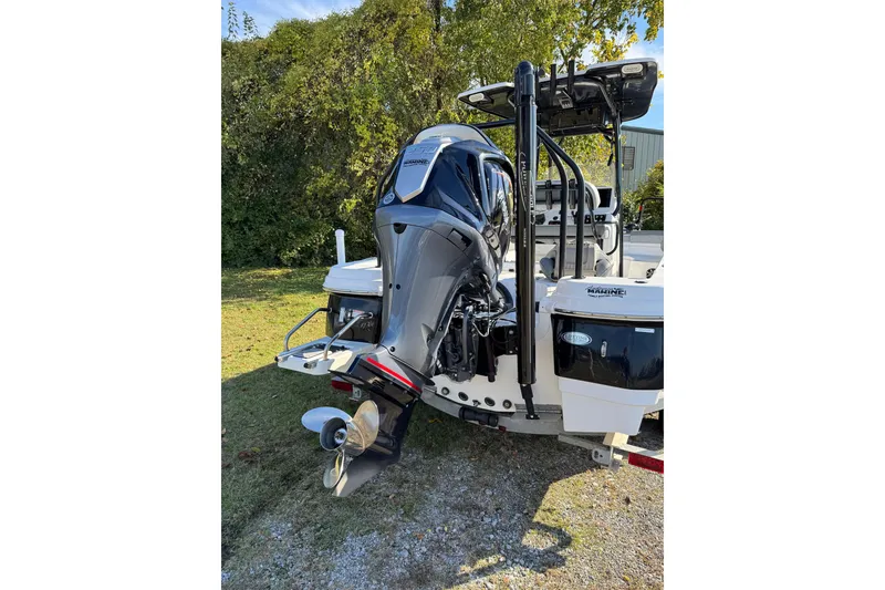 Slide: The Image of 2024 NauticStar 231 Hybrid boat with powerful outboard motor, parked on grass. - 3