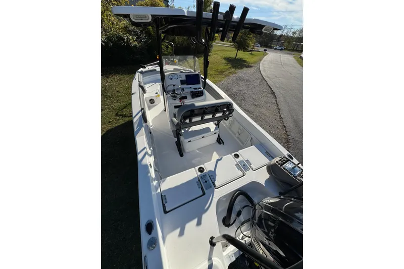 Slide: The Image of 2024 NauticStar 231 Hybrid boat interior with console and seating, parked on grass. - 4