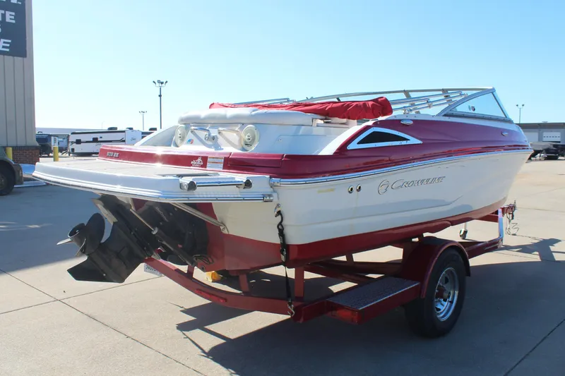 Slide: The Image of 2019 Crownline 205 SS boat in red and white on a trailer, parked outdoors. - 7