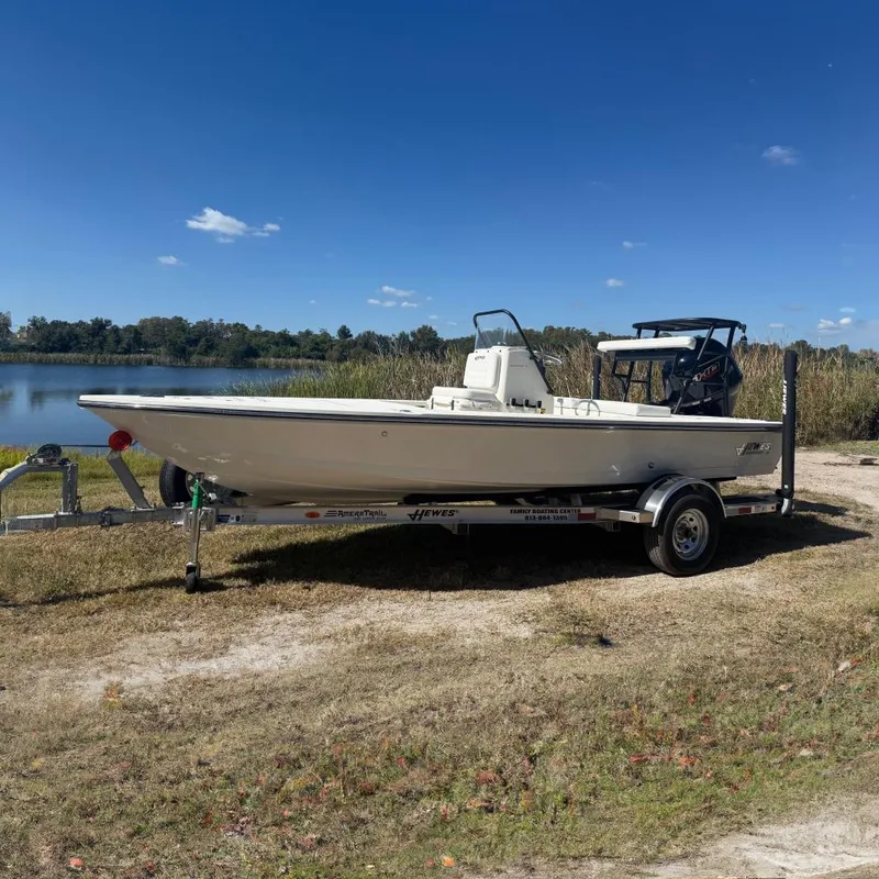 The Image of 2026 Hewes 18 Redfisher boat on trailer by a lake under clear blue sky. - 0
