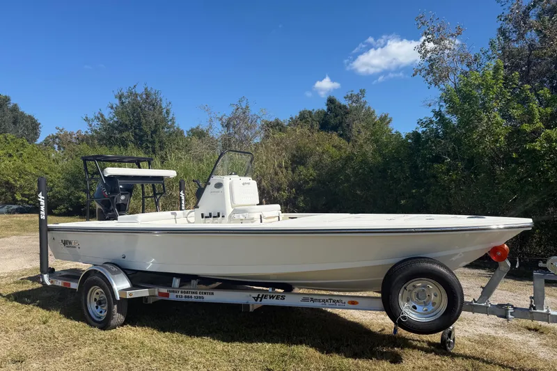 Slide: The Image of 2026 Hewes 18 Redfisher boat on trailer, parked outdoors with trees in background. - 10