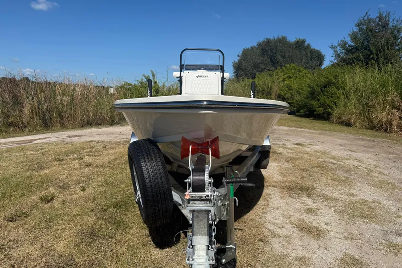 Slide: The Image of 2026 Hewes 18 Redfisher boat on trailer, parked on grassy area under clear blue sky. - 11