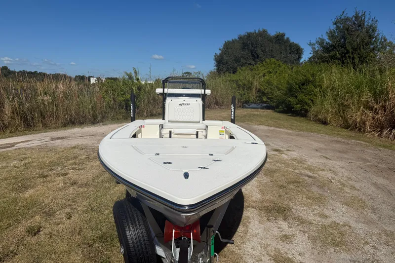 Slide: The Image of 2026 Hewes 18 Redfisher boat on trailer, parked on grassy area under clear blue sky. - 12