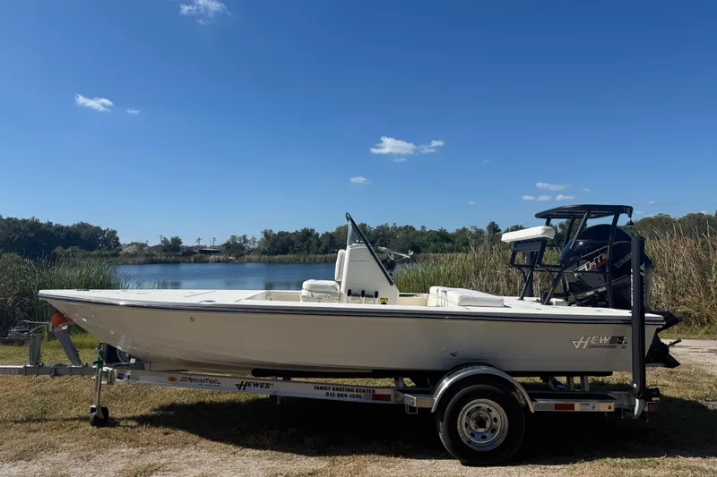 Slide: The Image of 2026 Hewes 18 Redfisher boat on trailer by a lake under clear blue sky. - 2