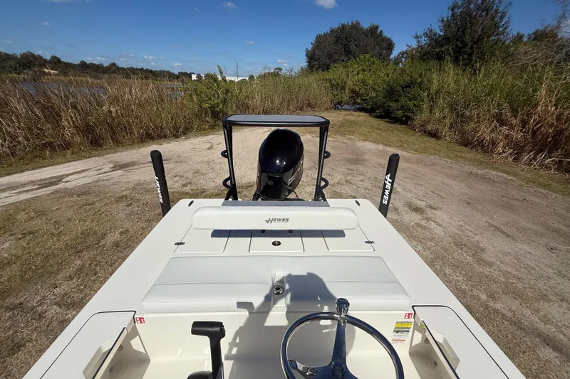 Slide: The Image of 2026 Hewes 18 Redfisher boat on a grassy path, showcasing steering and motor. - 20