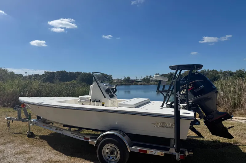 Slide: The Image of 2026 Hewes 18 Redfisher boat on trailer by a lake under clear blue sky. - 3