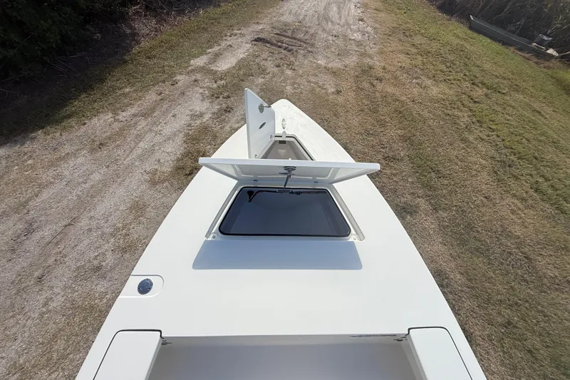 Slide: The Image of 2026 Hewes 18 Redfisher boat with open hatch, parked on grassy terrain. - 30