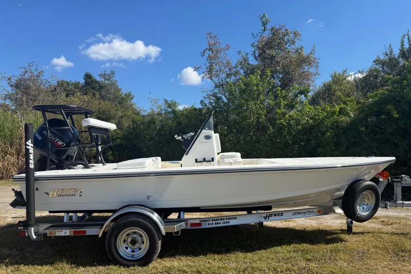 Slide: The Image of 2026 Hewes 18 Redfisher boat on trailer, parked outdoors under clear blue sky. - 9