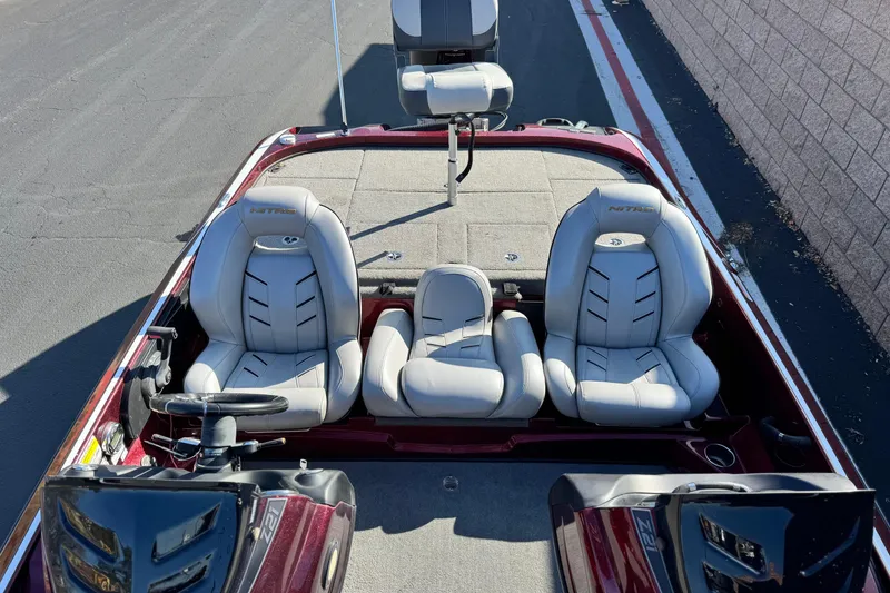 Slide: The Image of 2019 Nitro Z21 boat interior with three seats and steering wheel, parked on pavement. - 15