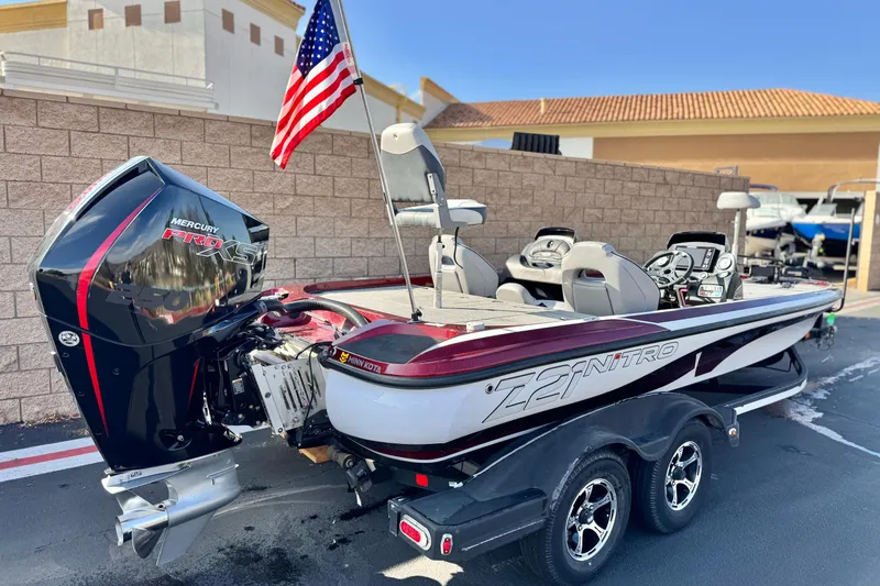 Slide: The Image of 2019 Nitro Z21 boat with Mercury Pro XS engine and American flag, parked outdoors. - 5
