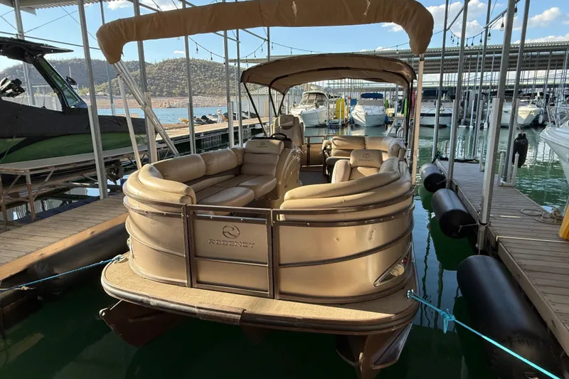 Slide: The Image of 2015 Regency 250 LE pontoon boat docked at marina with scenic background. - 3