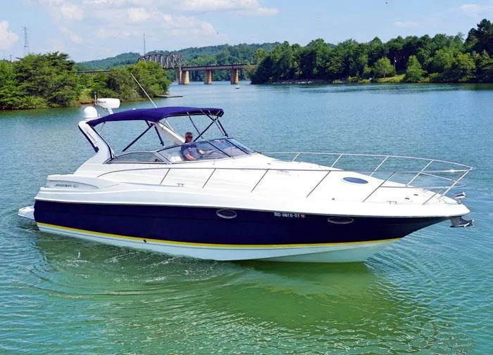 The Image of 2006 Regal Commodore 3560 yacht cruising on a scenic lake with lush greenery. - 0