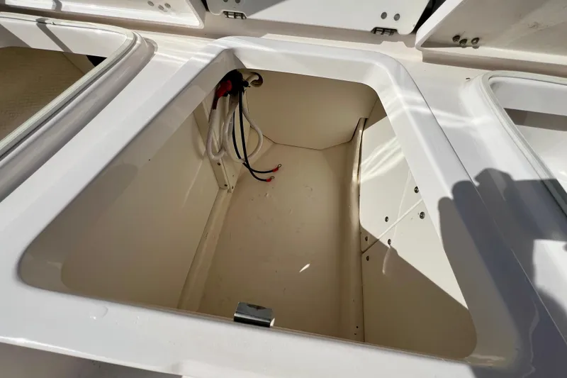 Slide: The Image of 2024 Robalo 206 Cayman storage compartment with wiring, open and sunlit. - 22