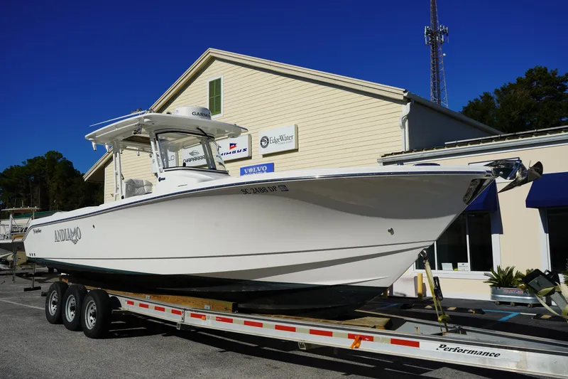Slide: The Image of 2021 Edgewater 320CC boat on trailer outside a building under clear blue sky. - 1